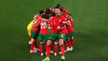 Cristiano Ronaldo celebrates with passion while the background includes the Portugal national team hugging each other. (Source: GOATTWORLD X)
