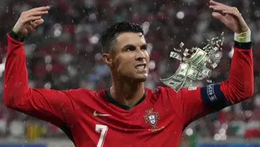 Cristiano Ronaldo puts his hands up while wearing the Portuguese jersey and flying money is next to him. (Source: GOATTWORLD X)