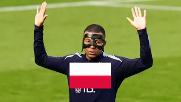 Kylian Mbappé raises his hands up while wearing a black mask and the Poland flag is in the middle. (Source: AP)