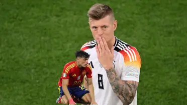 Toni Kroos blows a kiss the the crowd with a Germany jersey on while Pedri is on the ground with a Spain jersey on. (Source: Getty Images)